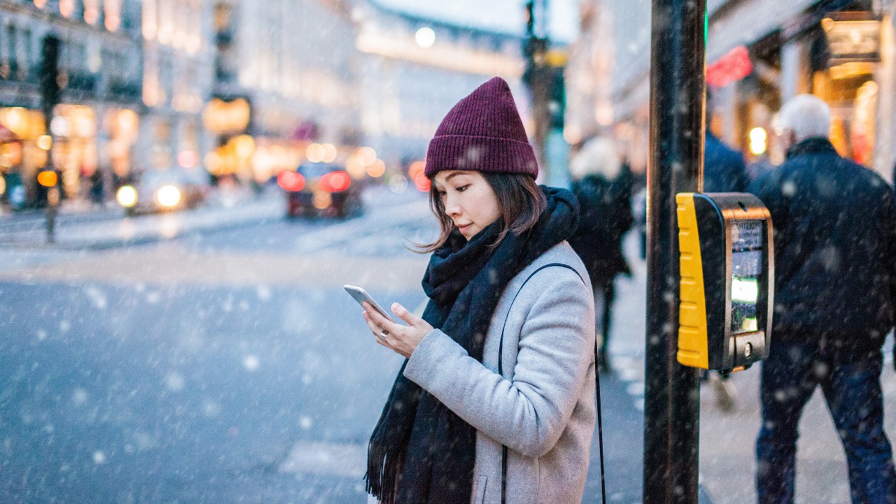 An Asian girl is using smartphone on street; image used for HSBC Singapore 9 essential foreign exchange travel tips article