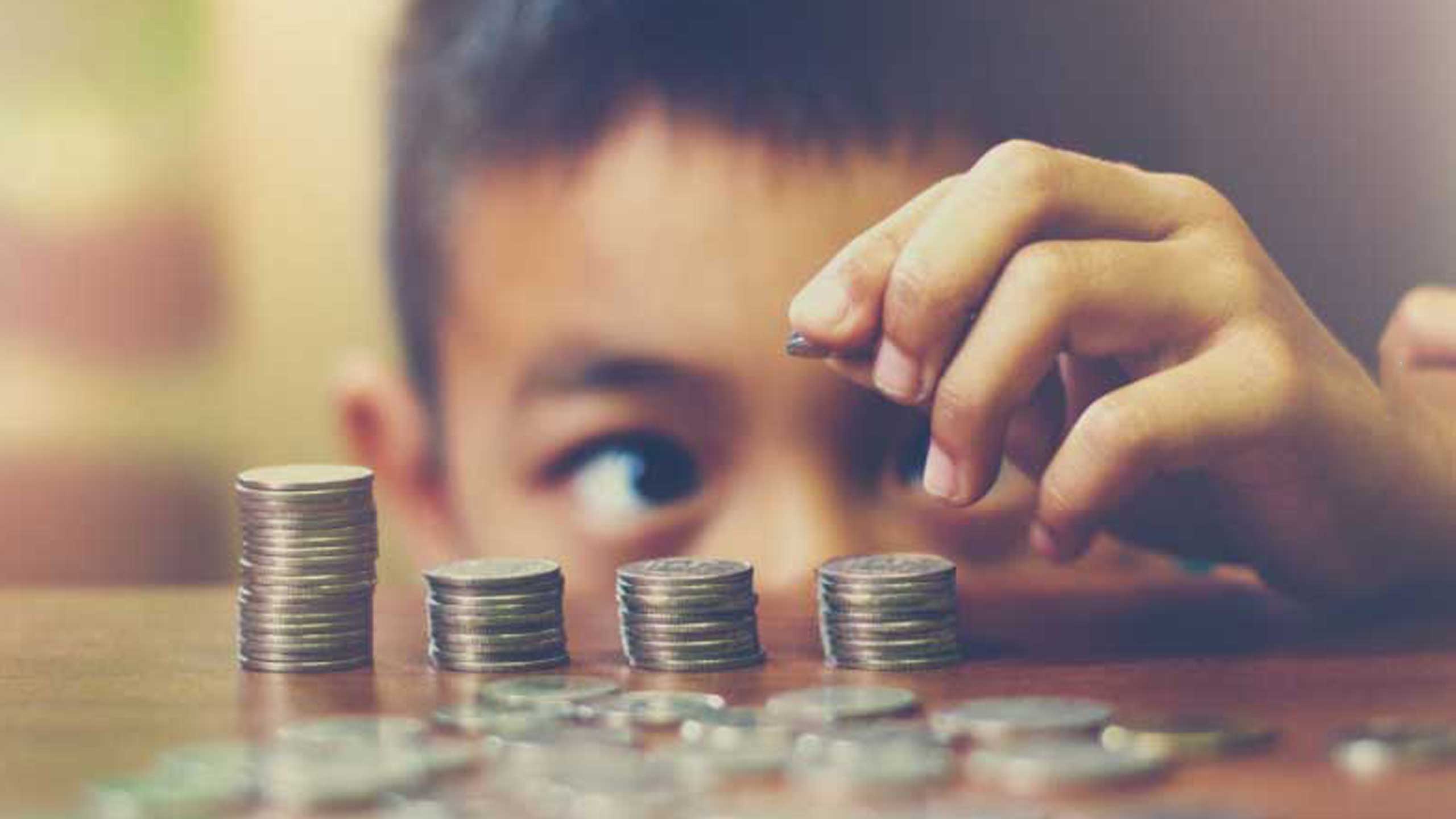 一个男孩在桌上堆硬币；图片使用于汇丰新加坡4种您应该了解的投资工具文章。