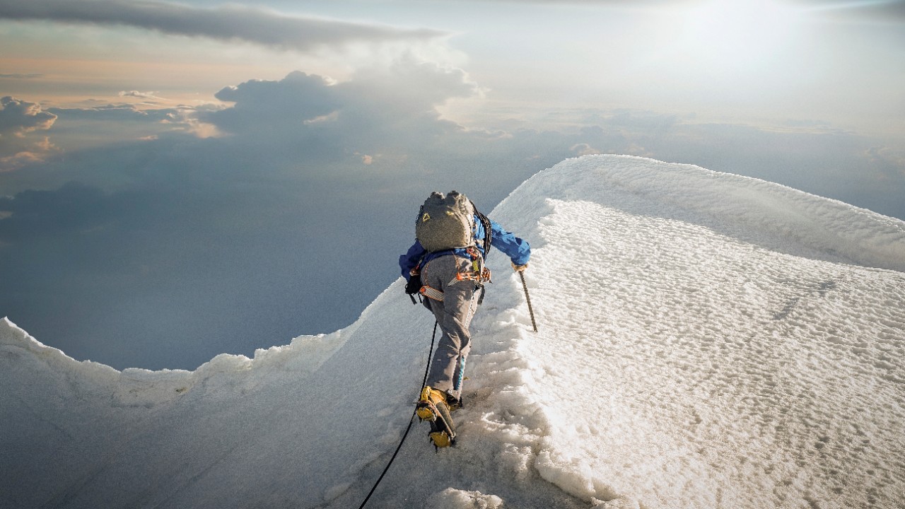 白雪皑皑的山脊上一名攀登者正在登山；图片使用于介绍汇丰新加坡实用的投资技巧文章。