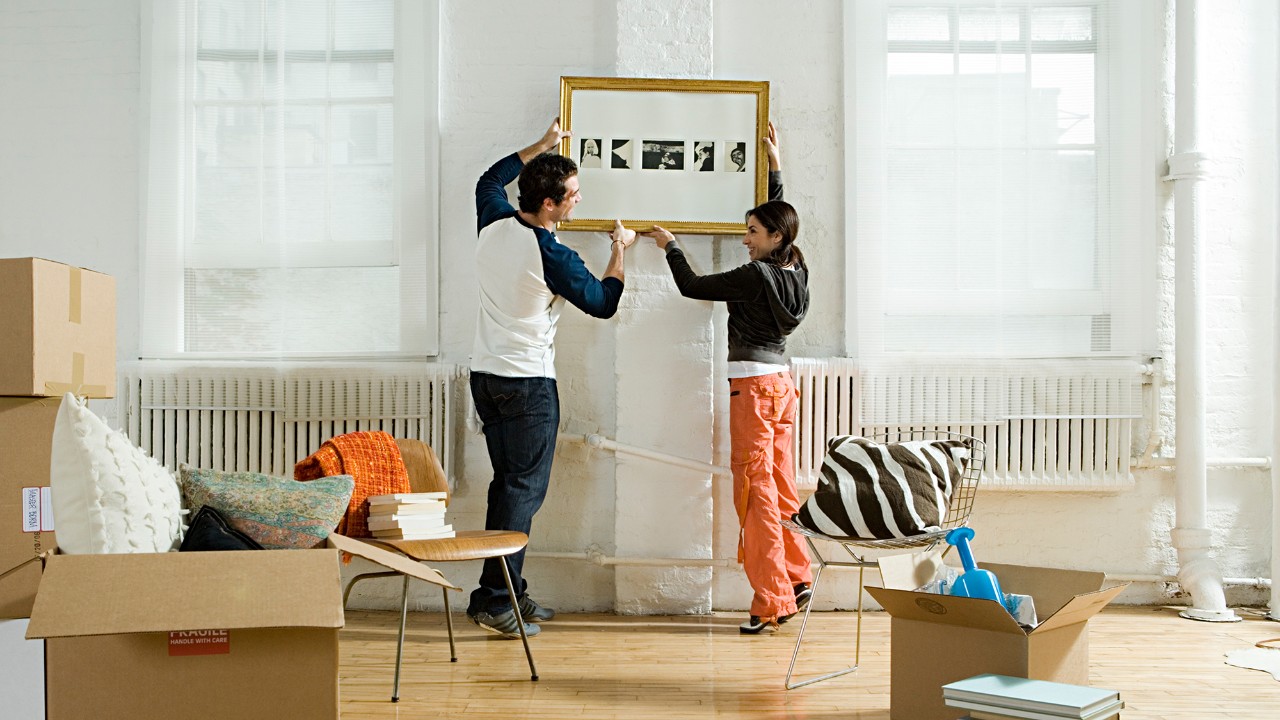 Couple hanging a picture on the wall; image used for HSBC Singapore home rewards.