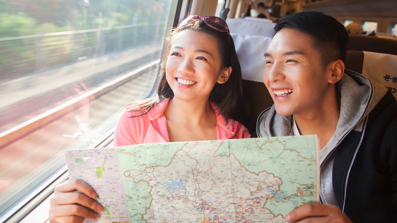 Couple on a train looking at a map; image used for HSBC Singapore travel and leisure rewards.