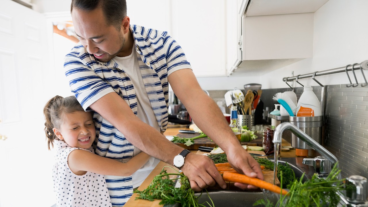 一对父女在厨房清洗蔬菜；图片使用于介绍汇丰保险产品。
