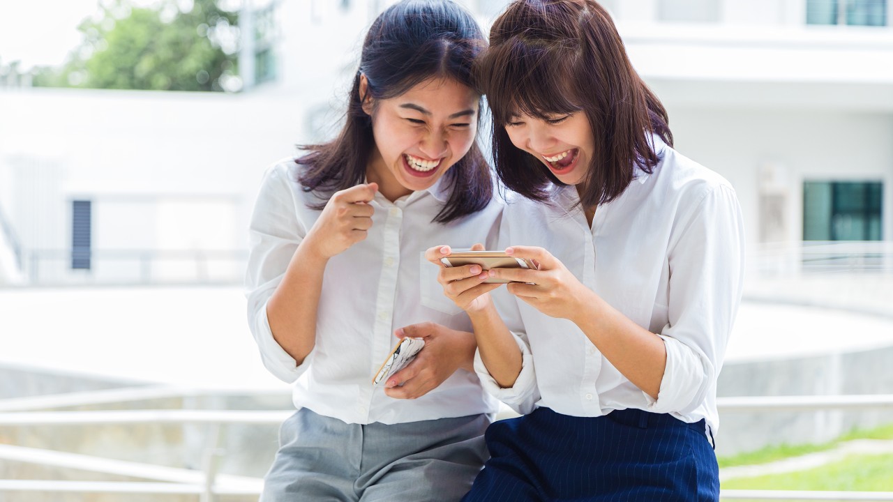 Friends using mobile phone together; image used for HSBC Everyday Global Account.