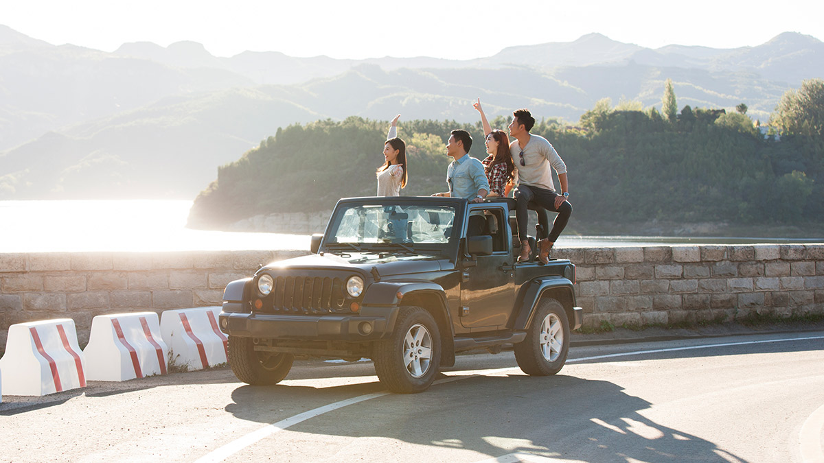 Men and women are standing on a car; image used for HSBC Car Insurance.