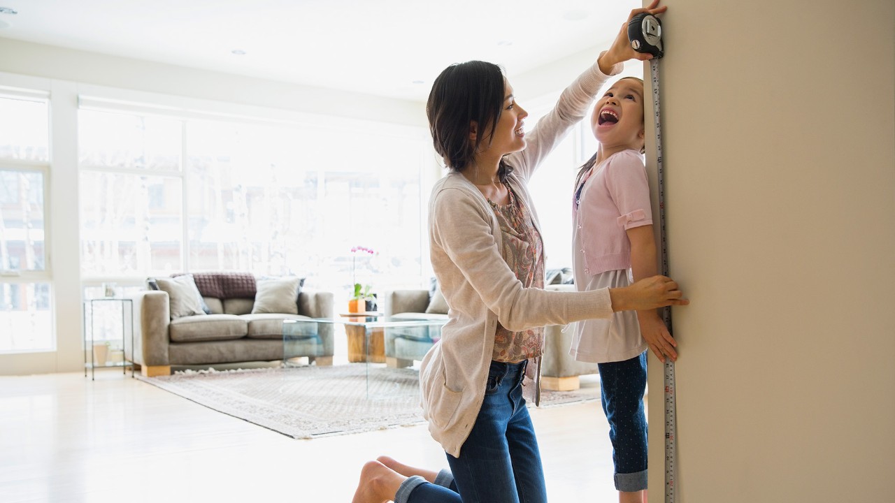A mother is measuring her daughter's height; image used for HSBC Singapore Time Deposit Account.