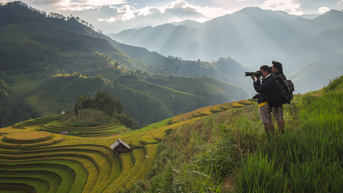Two men are taking photos at terraced field; image used for HSBC Travel Insurance.