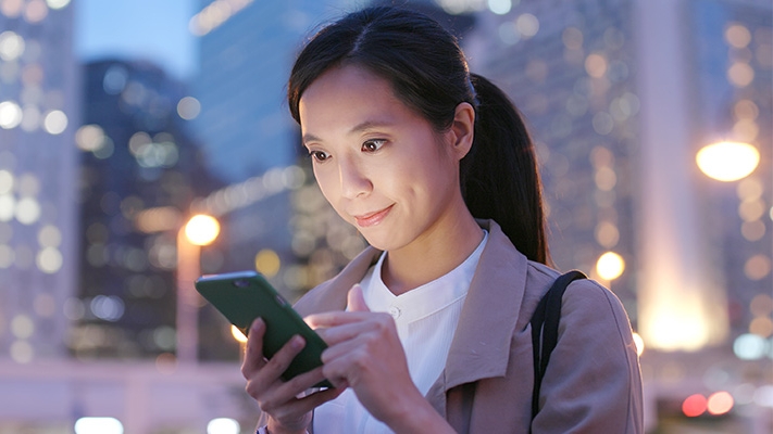 一位女士在夜晚使用手机；图片使用于汇丰新加坡账户
