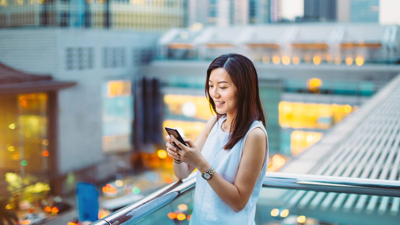 A woman is using her mobile phone; image used for HSBC Singapore Deposits.