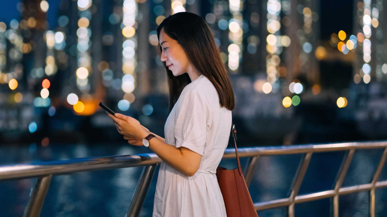 年轻女子在漫步道旁使用智能手机；图片使用于汇丰新加坡您需要知道的交易所交易基金文章。
