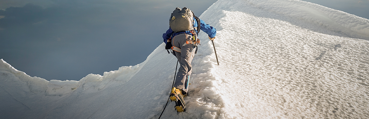 白雪皑皑的山脊上一名攀登者正在登山；图片使用于介绍汇丰新加坡实用的投资技巧文章。