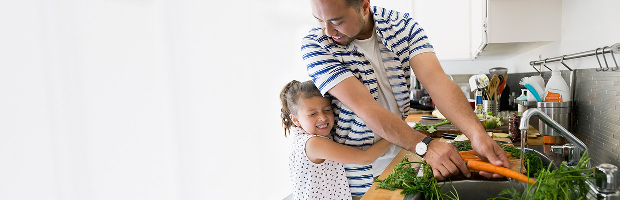一对父女在厨房洗菜；图片使用于汇丰保险产品页面。