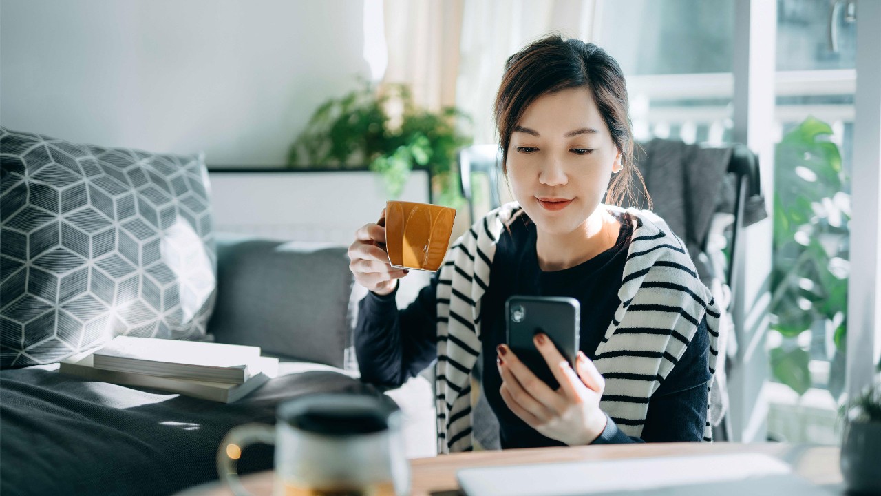 A woman using mobile to shop online at home; image used for HSBC Singapore Global Money Transfers.