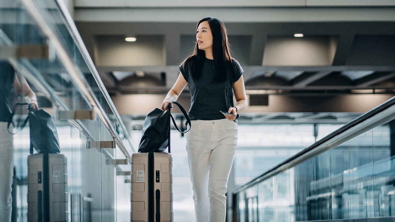 Woman carrying suitcase and passport; image used for HSBC International investors.
