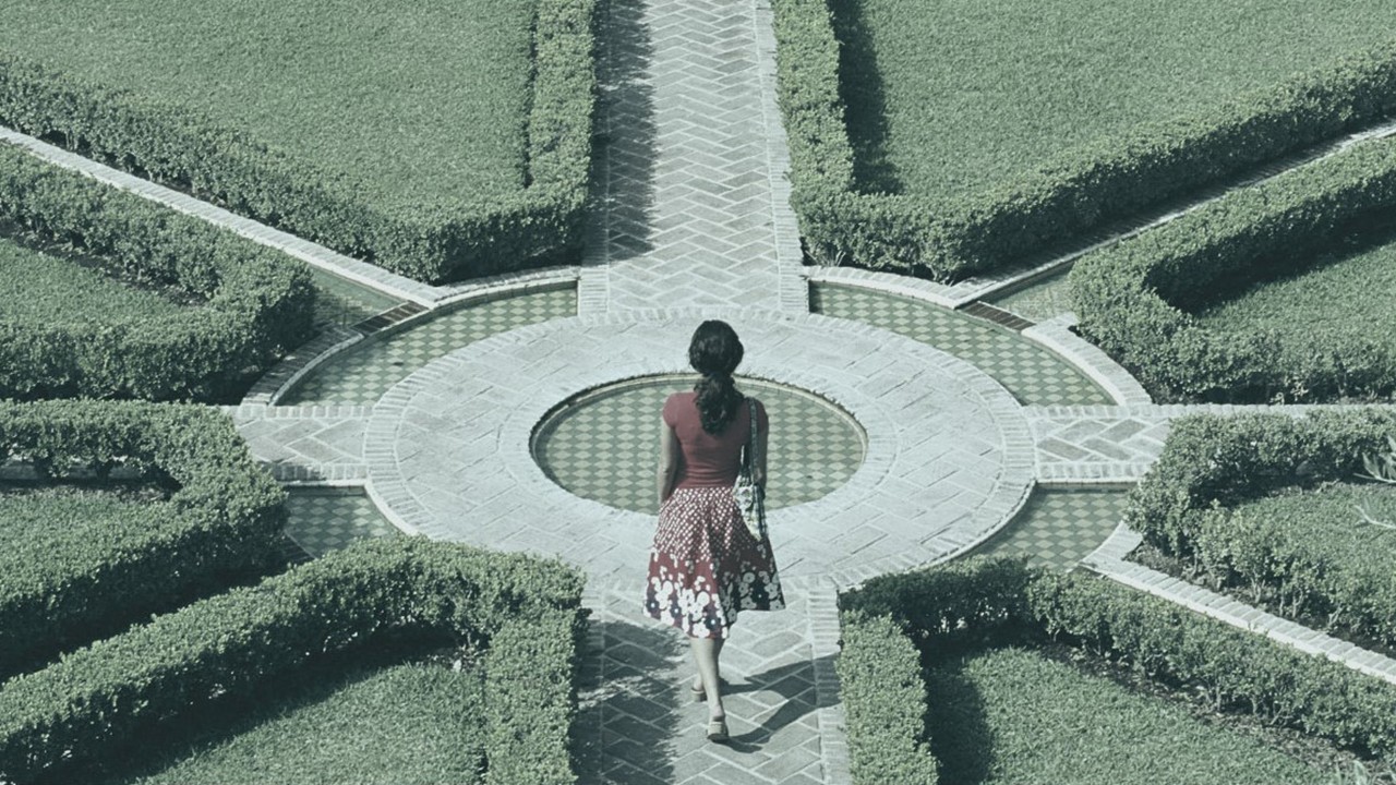 Woman exploring a hedge maze in the shape of a compas.