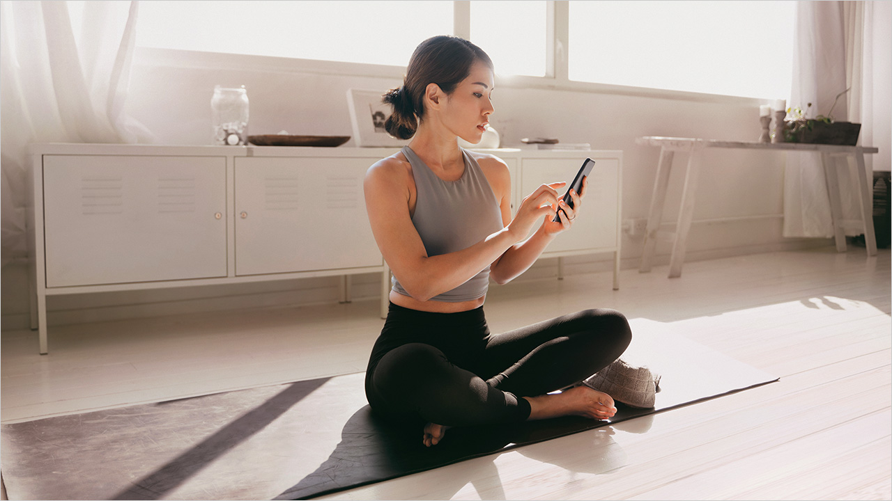 Woman using mobile phone in yoga mat; image used for HSBC Singapore Personal Loans.